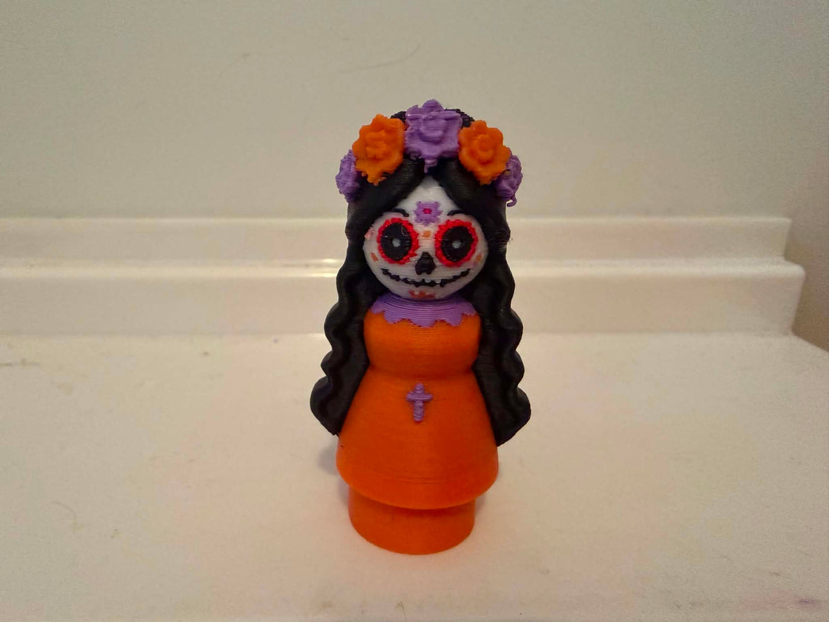 Catrina-style girl figurine front view with orange dress and colorful flower crown