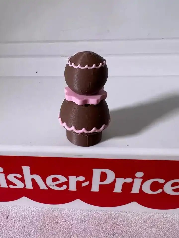 Pink-iced gingerbread pals figurine with two stacked dark-brown cookie figures