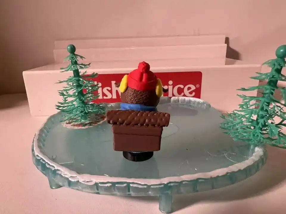 Christmas holiday figurine set with nutcracker-style figure holding a brown gift on icy base