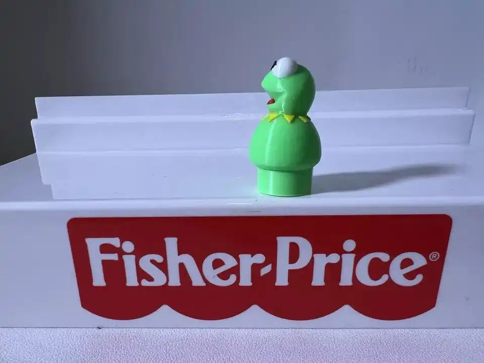 Green frog figurine standing upright, white eyes and open mouth, angled left