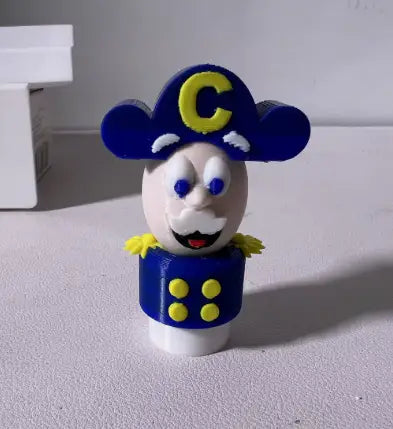 3D-printed cereal mascot figure with blue navy captain hat and buttoned uniform