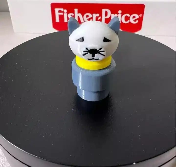 A custom Fisher-Price Little People figure of a gray cat with a yellow collar stands on a black surface.