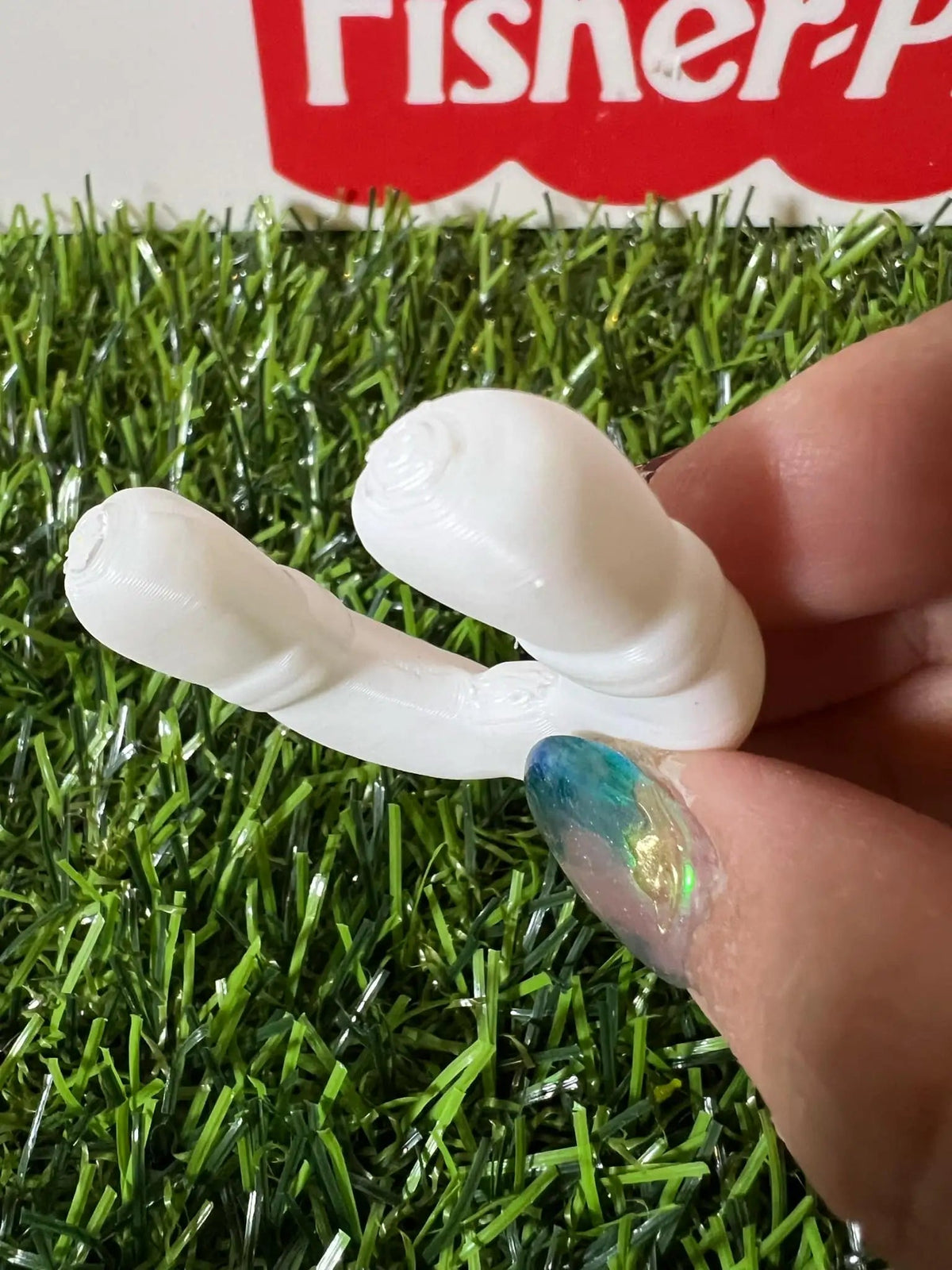 White plastic life preserver replacement ring held in hand on artificial grass