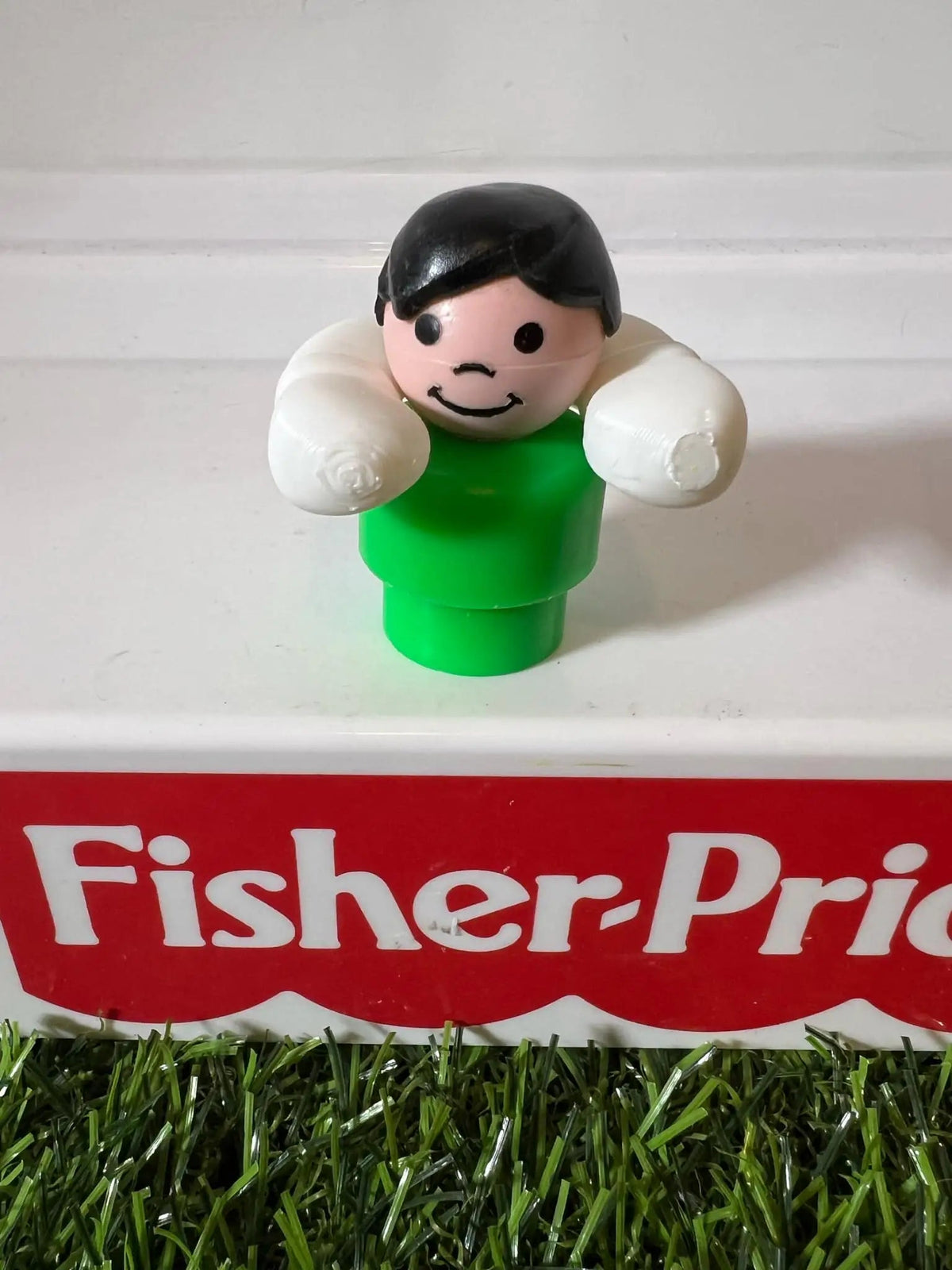 Fisher-Price toy figure with black hair, green shirt, and white gloves