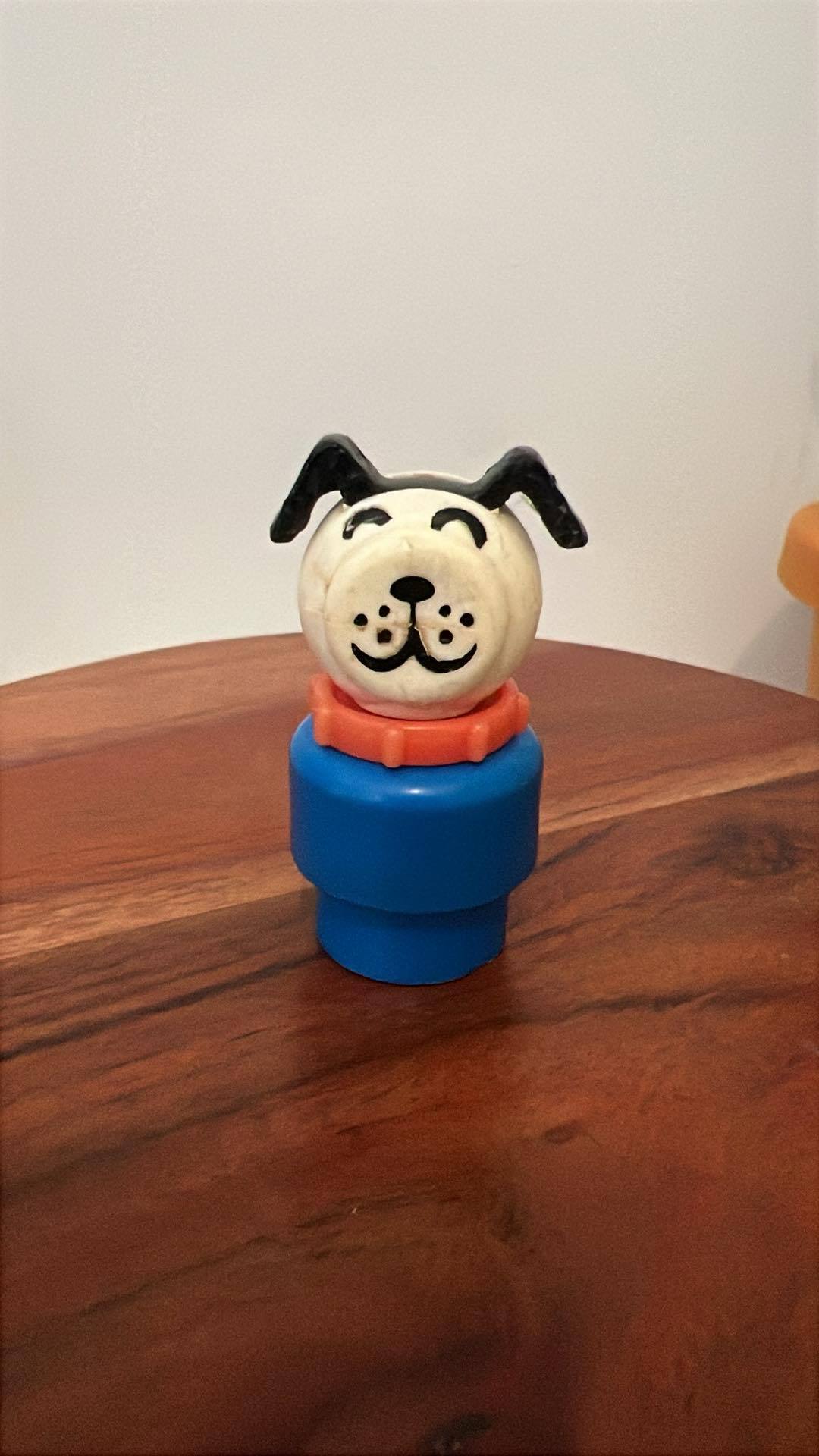 Dog-shaped toy figure with blue base and red collar on wooden table
