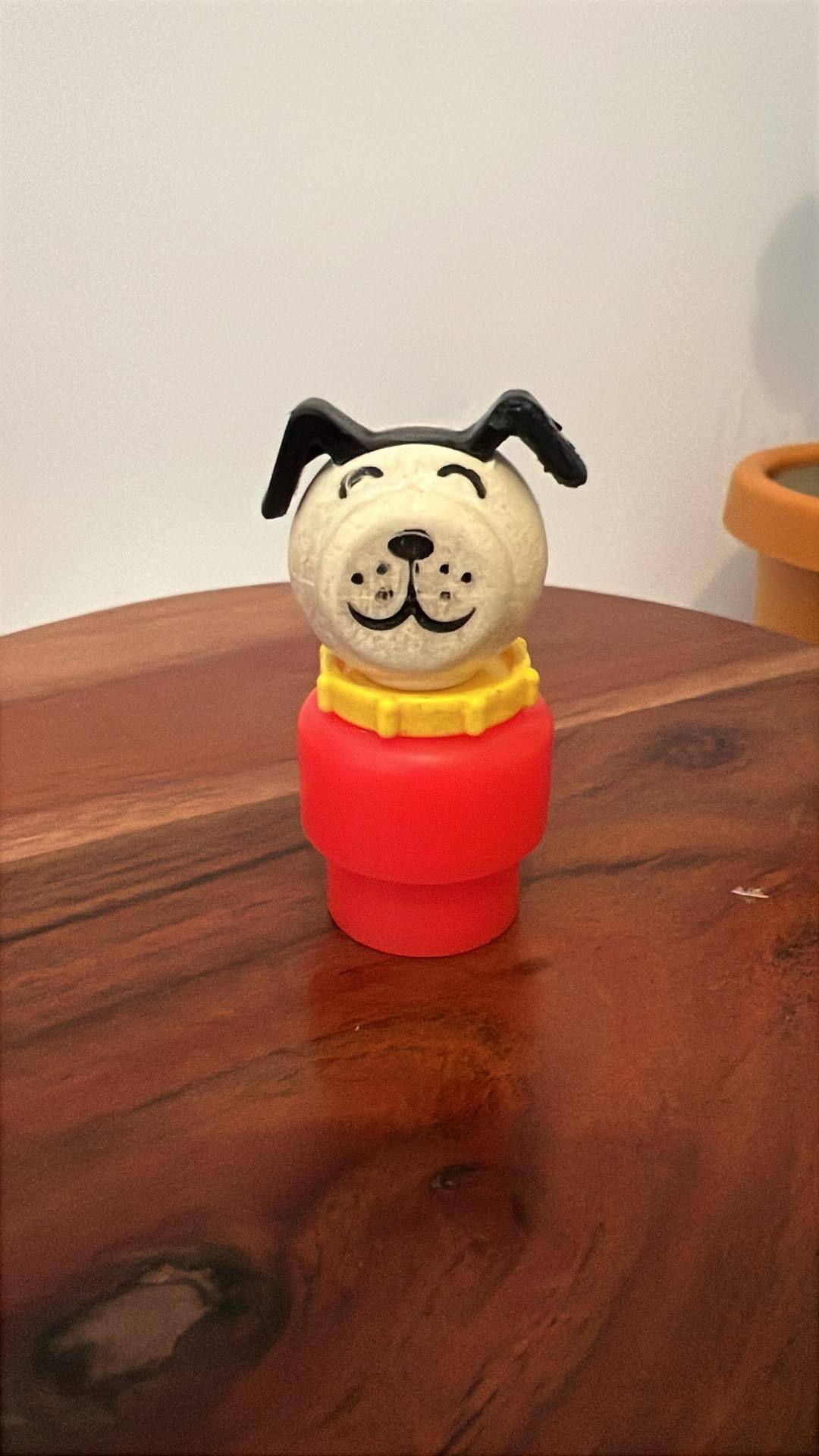 Stacked dog toy figure with black ears and red base on wooden surface