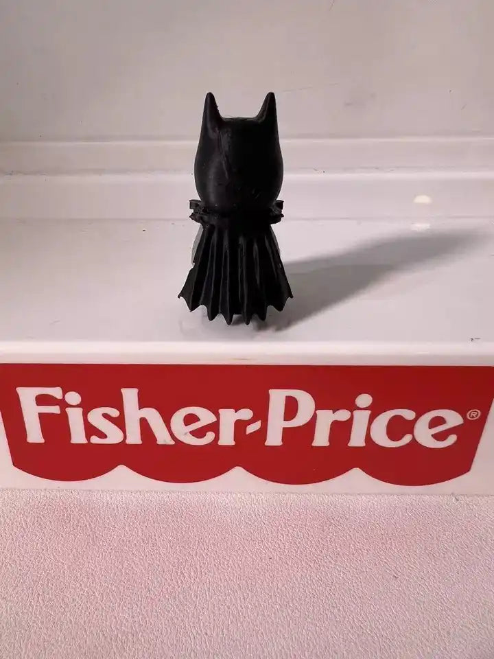 Batman mini figure standing on white base, black suit and cape