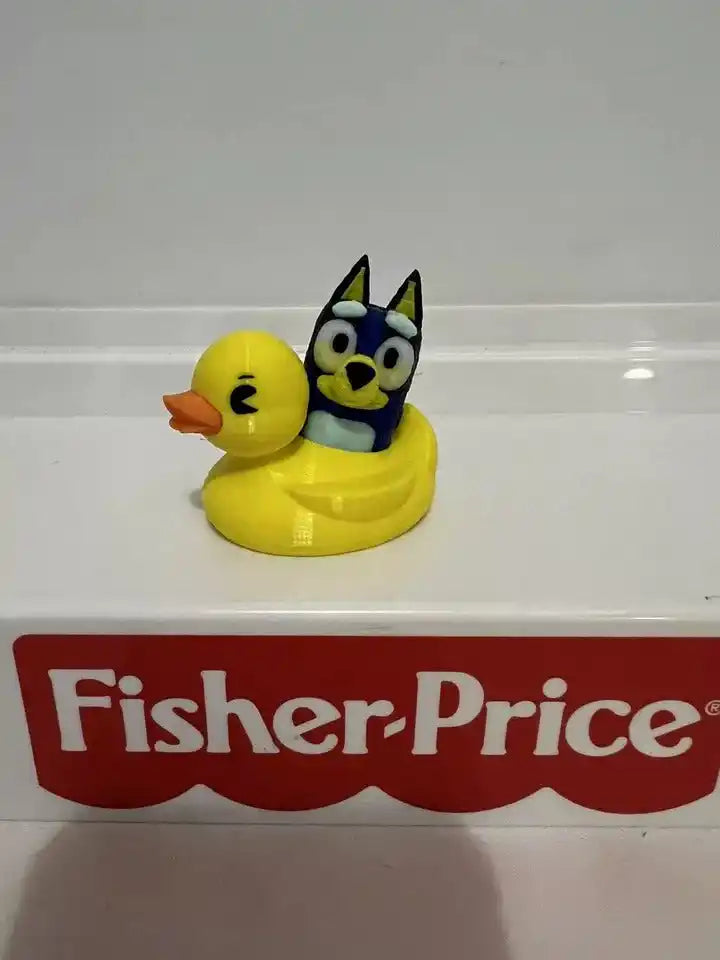 A custom 3D Bluey figure from the McDonald's Little People Style Collection sits in a yellow duck on a Fisher-Price display.