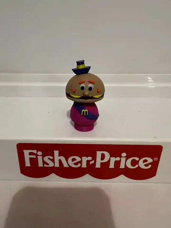 Mayor McCheese figurine with brown cheese head, magenta suit, blue top hat