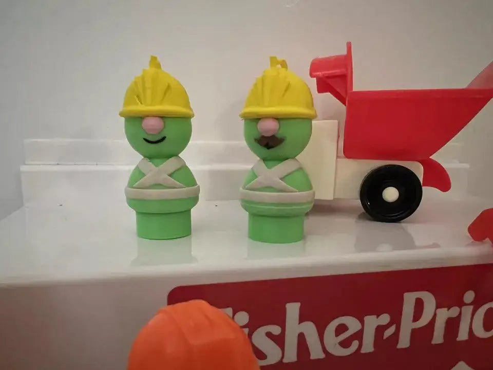 Green Doozer toy figure with yellow hat and white outfit, next to red cart