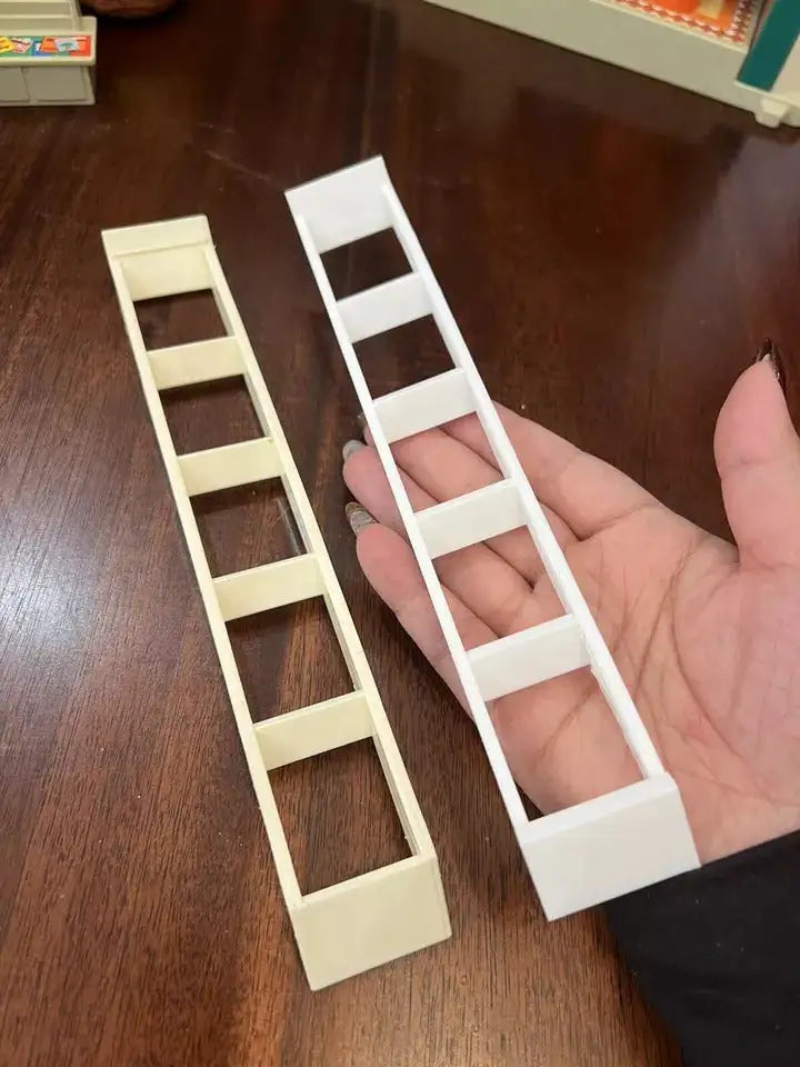 White Fisher-Price Little People replacement ladder pair with rungs, held in hand