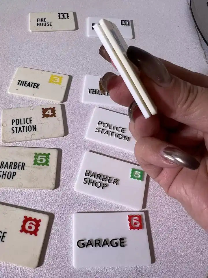 Hand holding a strip over Fisher Price replacement mail tiles: Theater, Police, Barber, Garage