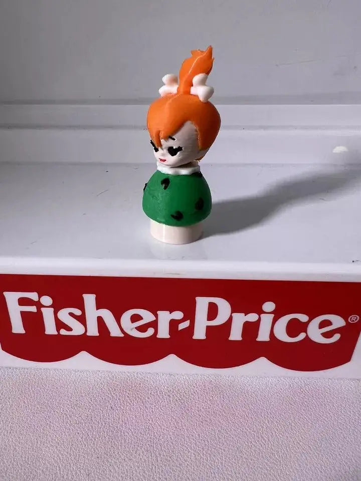 Pebbles Flintstones toy figure with orange hair tuft and green dress, side view