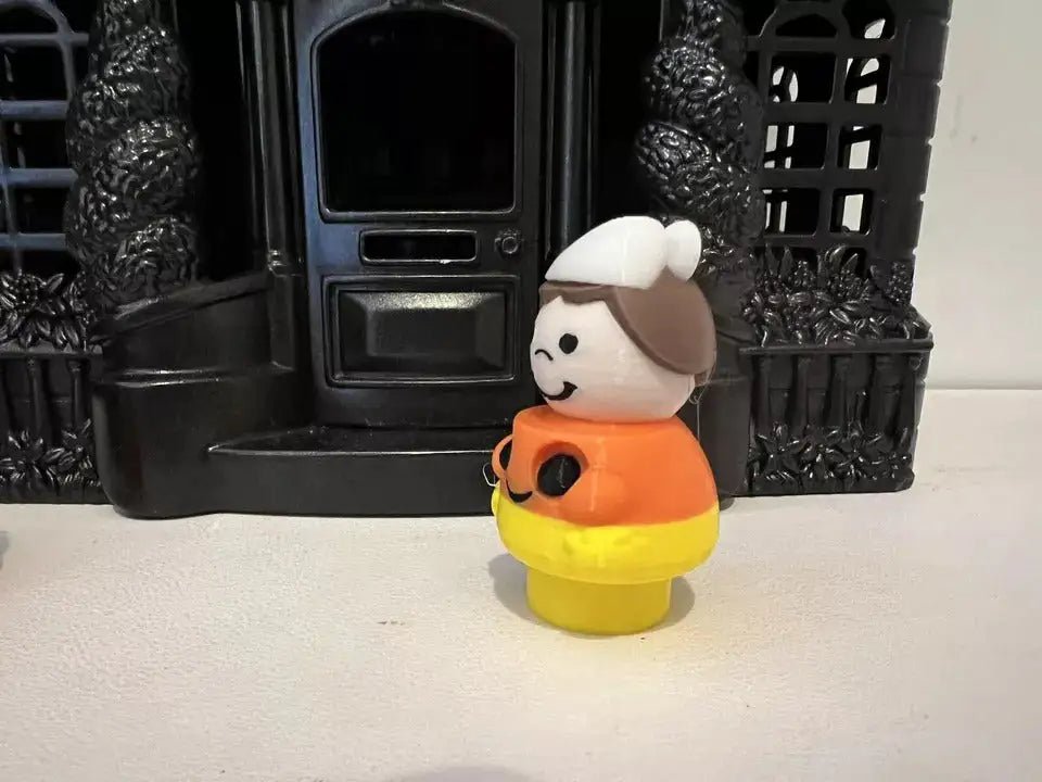 Candy corn girl figurine in profile with white bonnet, orange top, and yellow skirt.