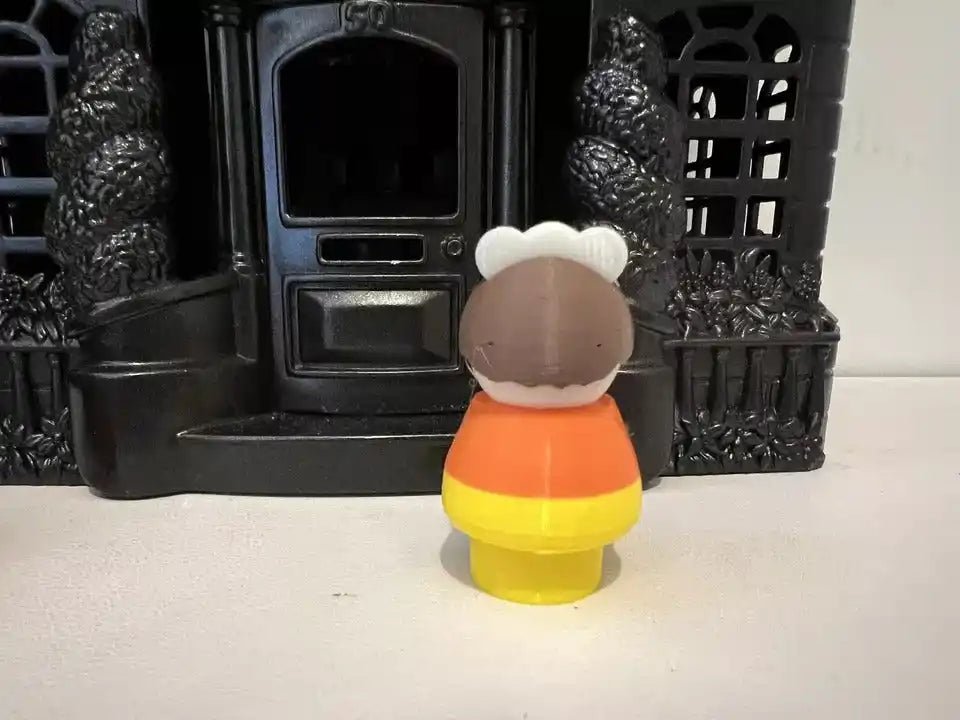 Back of candy corn girl figurine with white bonnet and orange/yellow outfit.