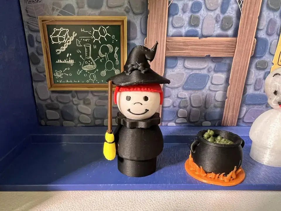 Halloween witch figurine with black hat, red trim, holding yellow broom