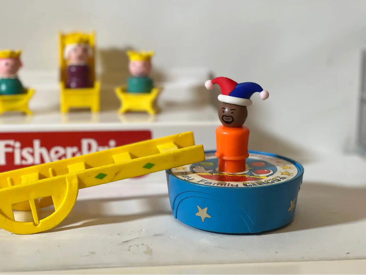 Small red-and-blue jester hat on a toy figure, tilted with white pom-poms
