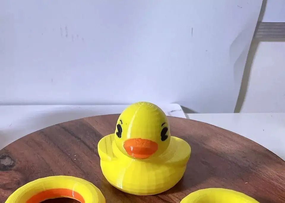 A "Jumbo Duck Floatie" custom art figure, yellow with an orange beak, sits on a wooden surface with two yellow rings.