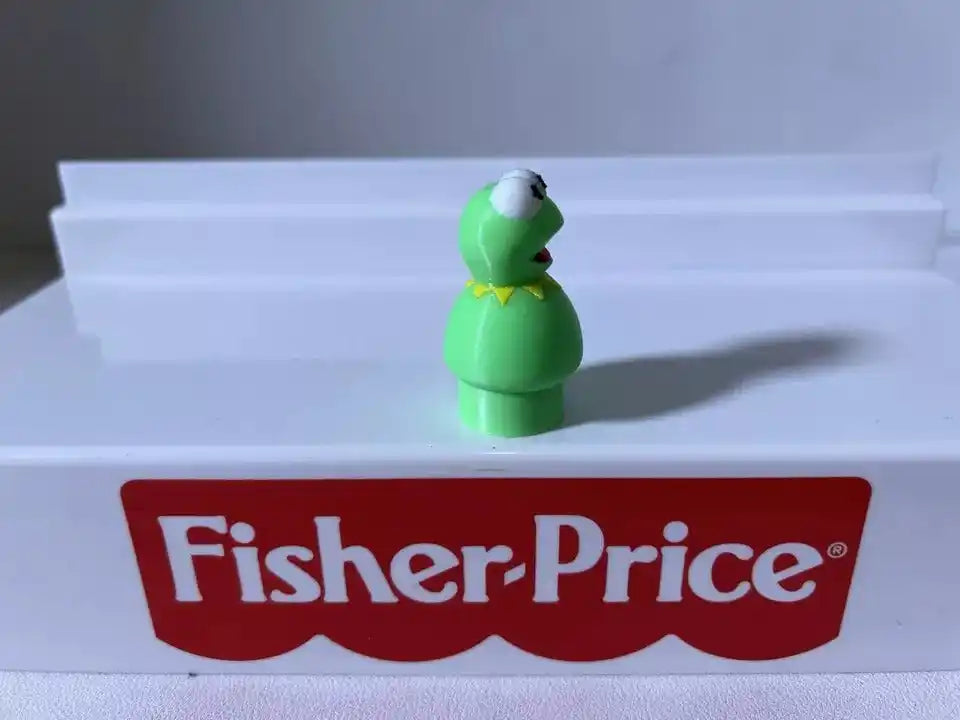 Green frog figurine standing on base with white eyes and open mouth, angled right
