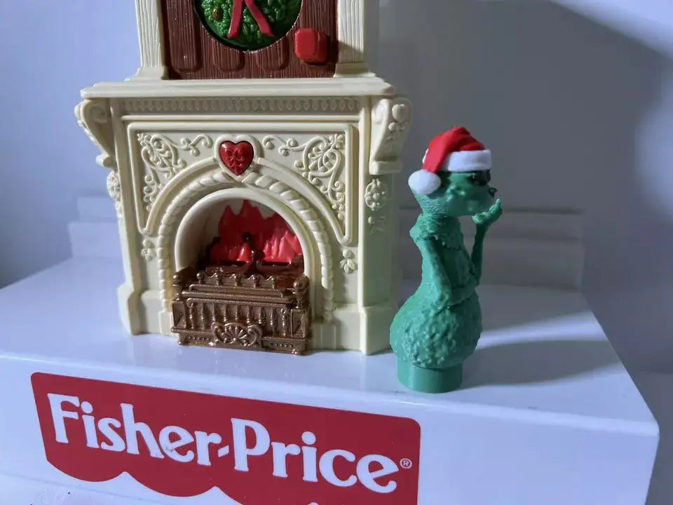 Fisher-Price holiday Grinch figure near white fireplace with red window and wreath