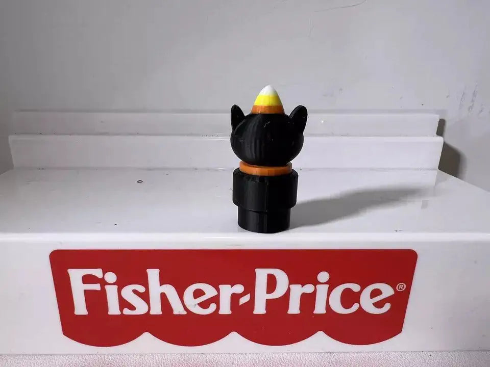Black cat figurine holding a multicolor wizard hat, rounded face details