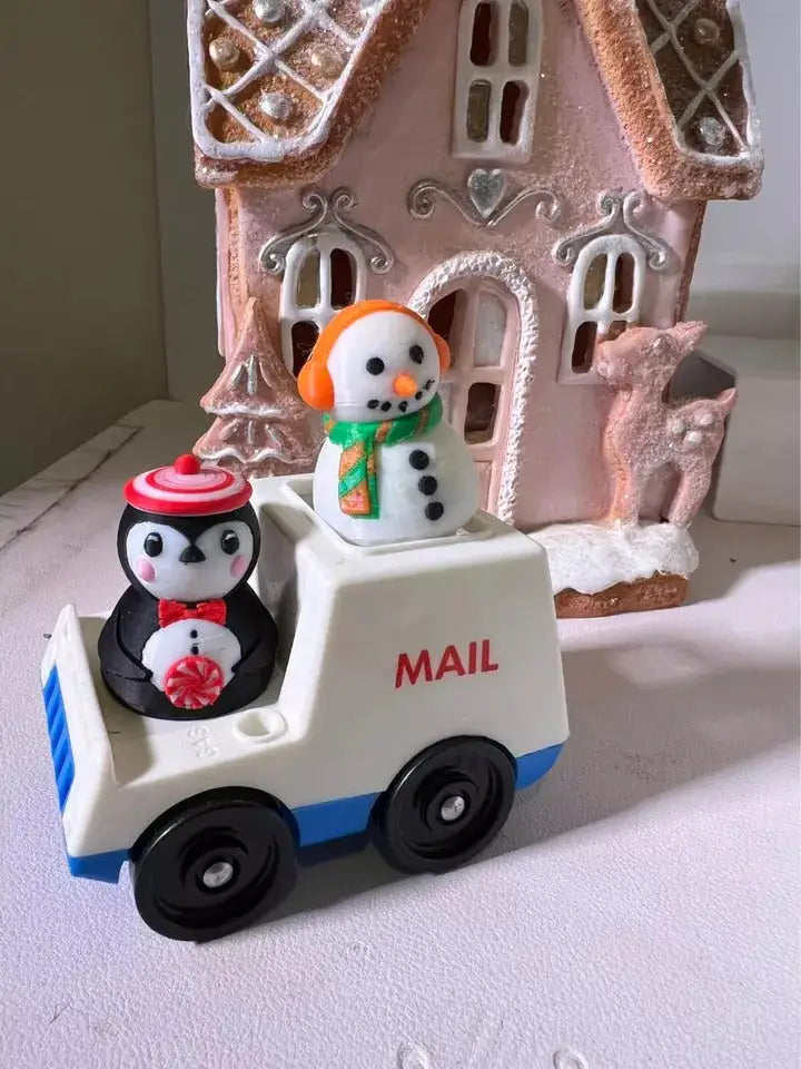 Two custom Fisher-Price Little People Christmas figures, a penguin and a snowman, ride in a "MAIL" truck