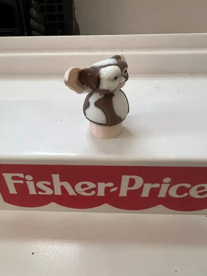 Front-facing brown-and-white dog figurine on round beige base