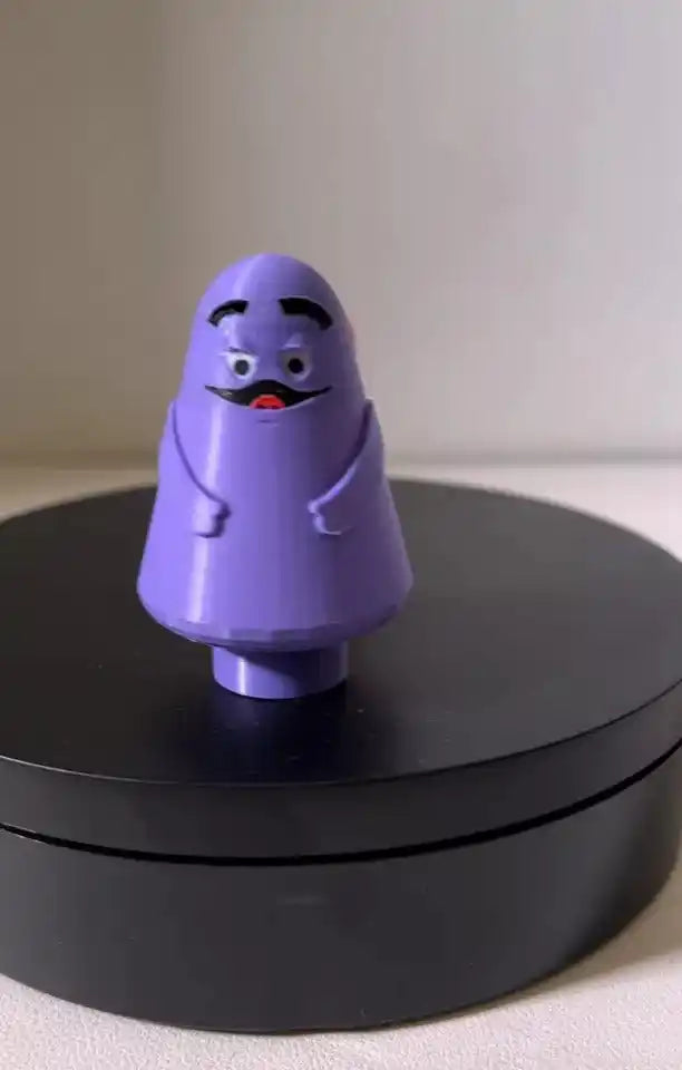 A custom 3D printed Little People style McDonald's Grimace figure stands on a black display base.