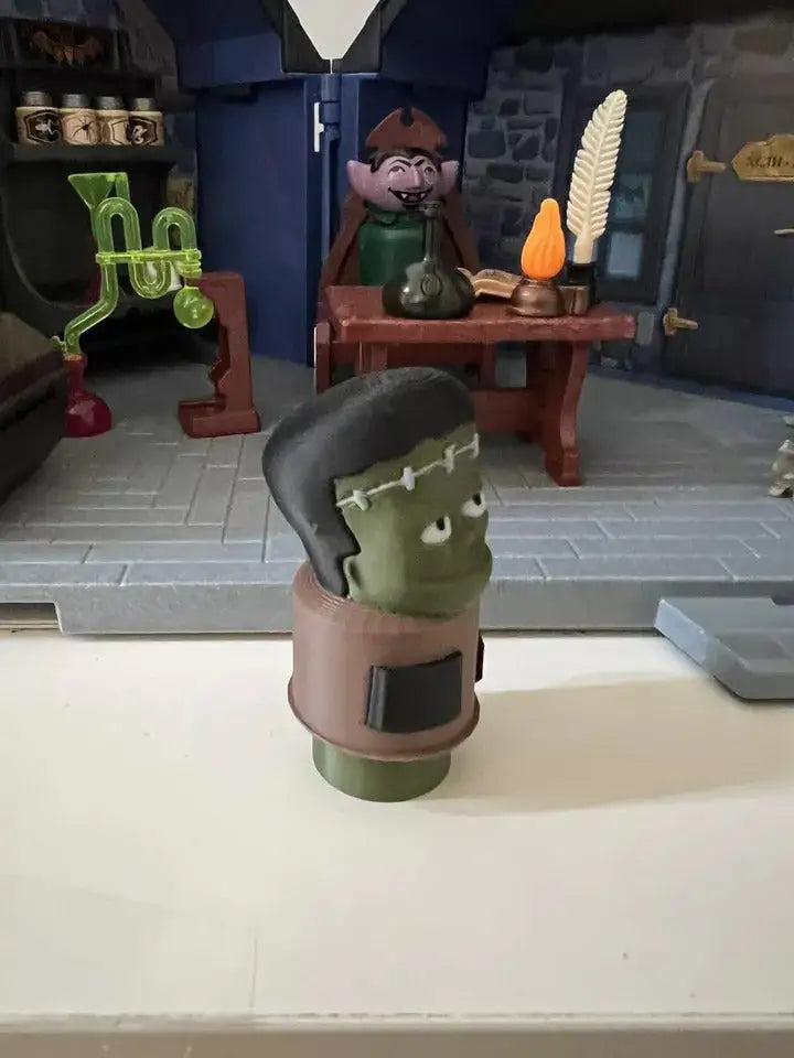 Frankenstein-style green figure with black hair cap and brown clothing band, Halloween decor