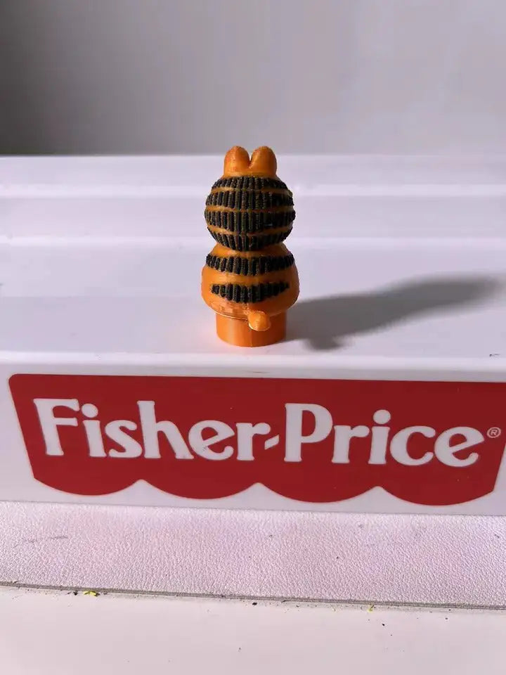 Orange cat toy figure wearing black striped hat and sweater