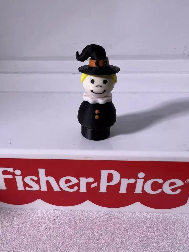 Halloween witch figurine, front view: black hat and dress with white face and yellow collar.