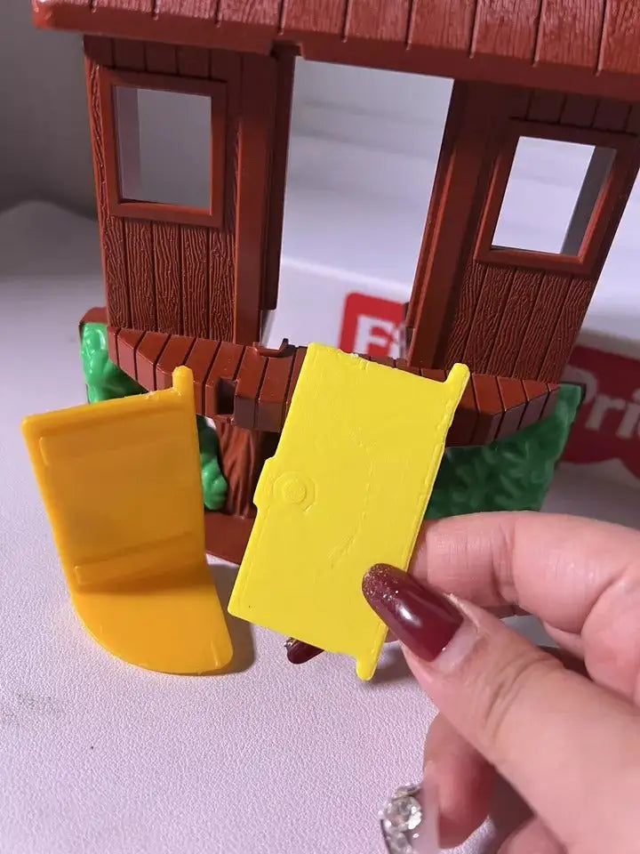 Hand holding yellow tree house door panel with raised text against door frame