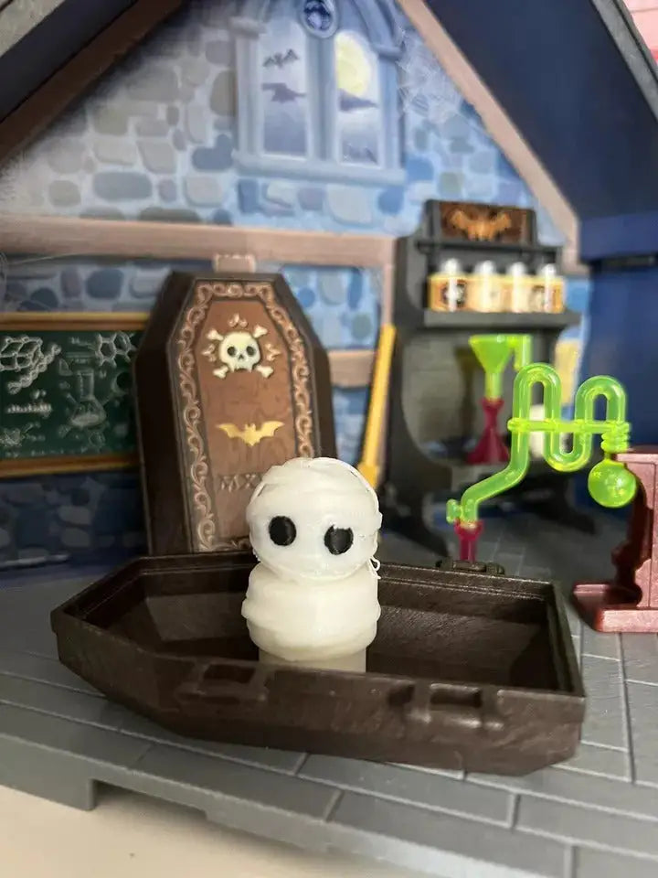 A custom Little People "Halloween - Mummy Boy" figure stands in a brown coffin accessory within a haunted house diorama.