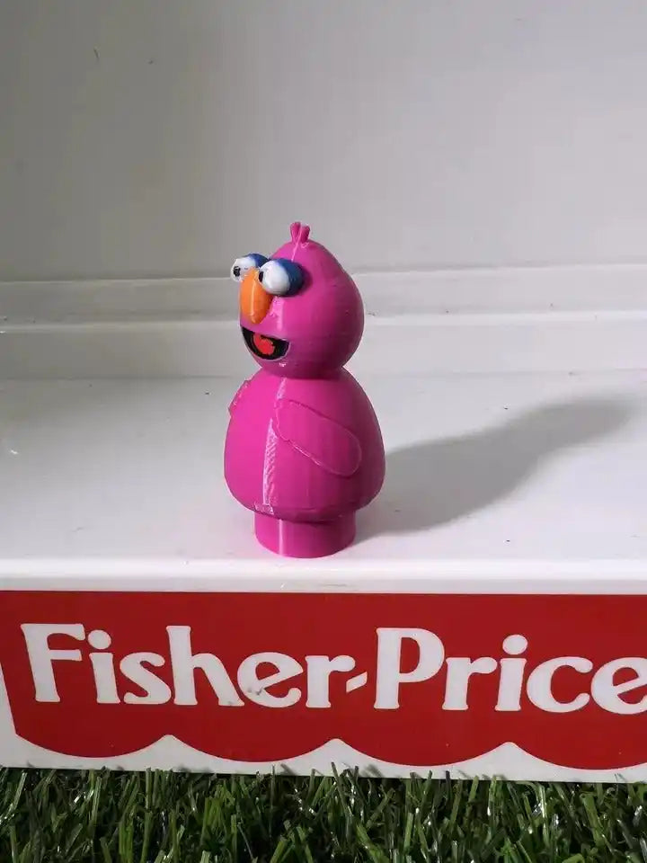 A 3D-printed Telly custom figure, inspired by Sesame Street, stands on a white shelf above a red Fisher-Price logo.