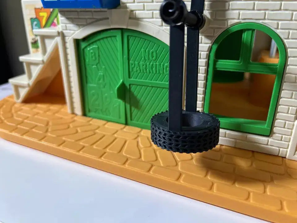 Dark gray tire swing on black plastic stand for toy playhouse