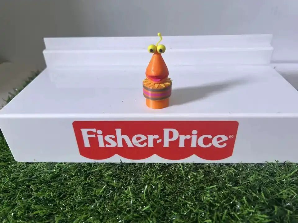 Orange bug character toy with green antennas on white step, Fisher-Price logo centered