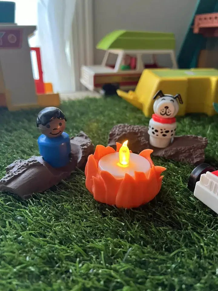 Toy campfire accessory with lit orange flame on brown logs and small figurines