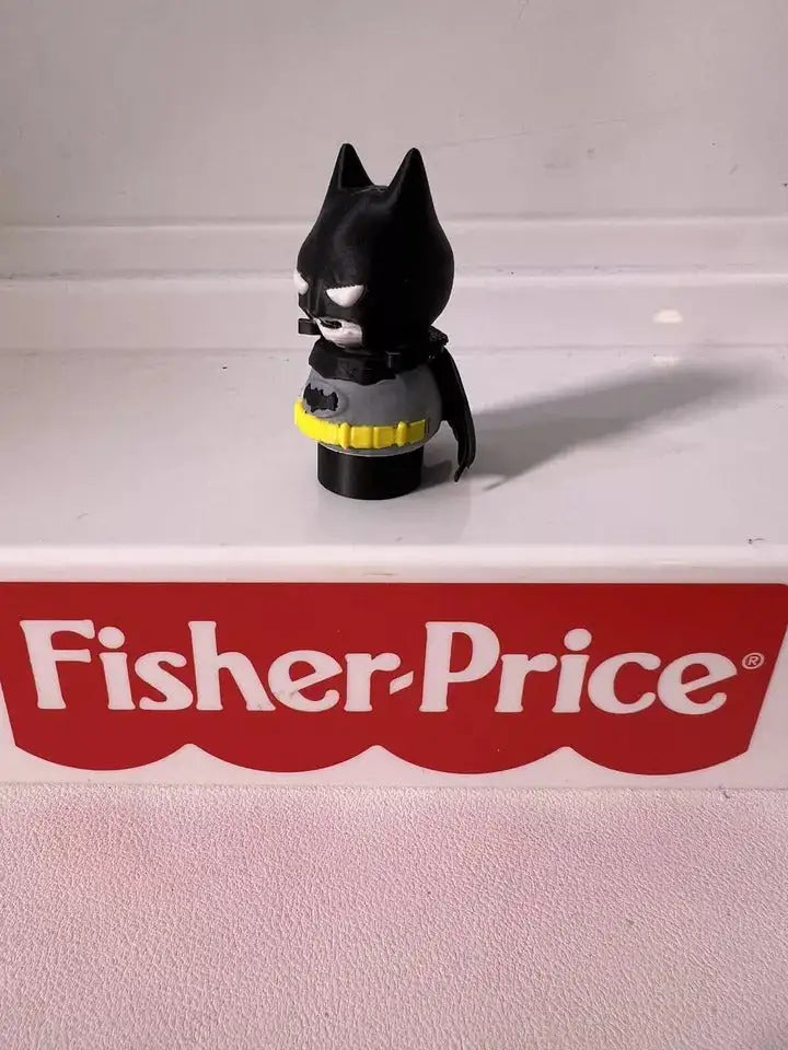 Batman mini figure from slight angle, black suit with yellow belt and cape