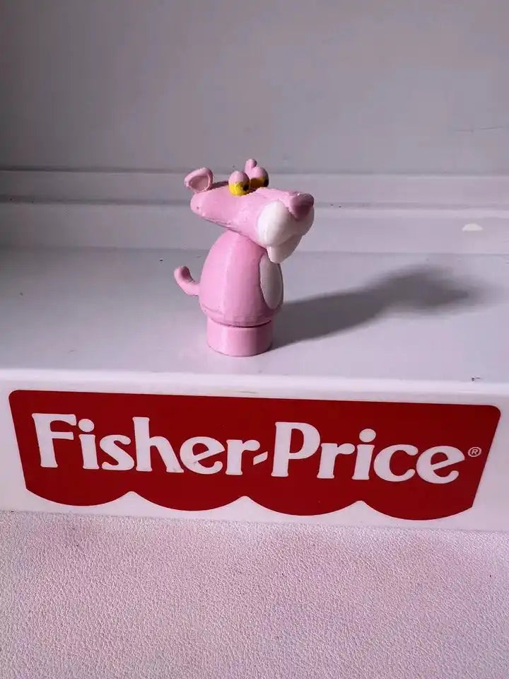 Pink panther toy figurine with yellow crown and raised arms, standing