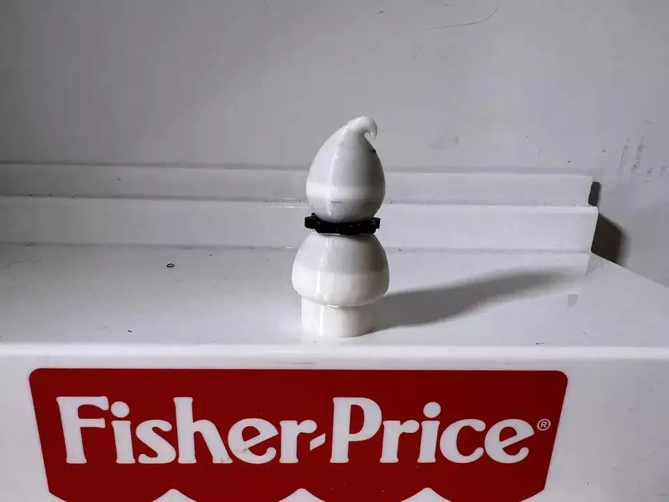 White ghost figurine standing upright with black dot face details
