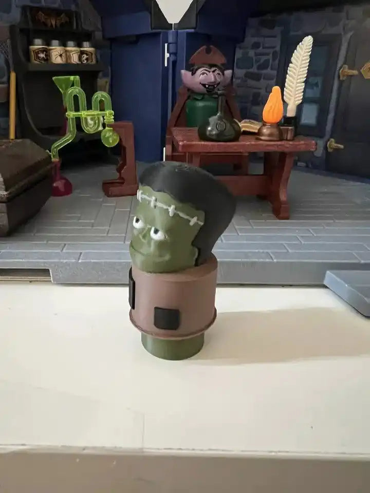 Green Frankenstein figurine with black side hairstyle, brown torso band, Halloween collectible