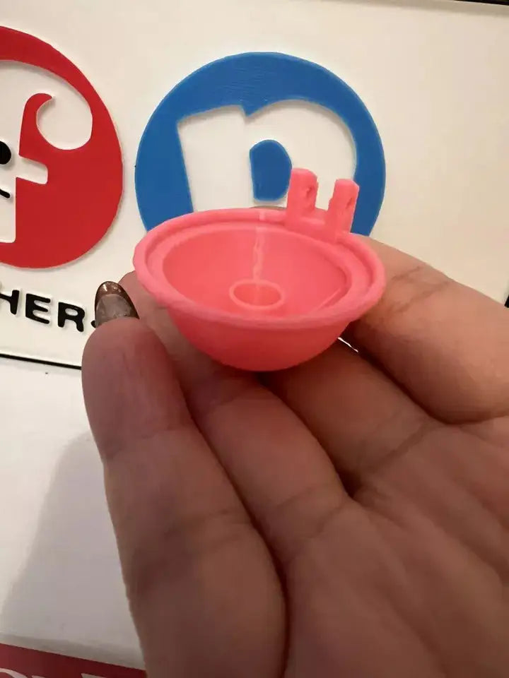 Pink replacement hair dryer nozzle cap underside, held in hand