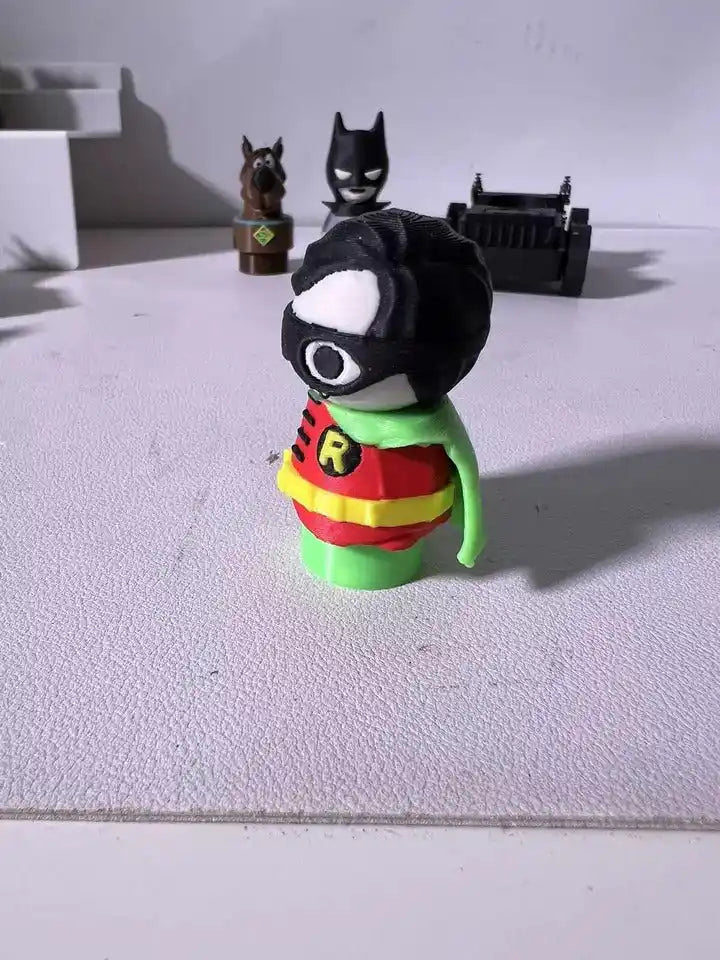 Robin character plush figure in profile, black mask with white eyes and green cape.