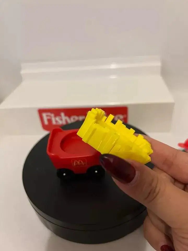 Red fry car adapter with yellow fries, hand holding on black round base
