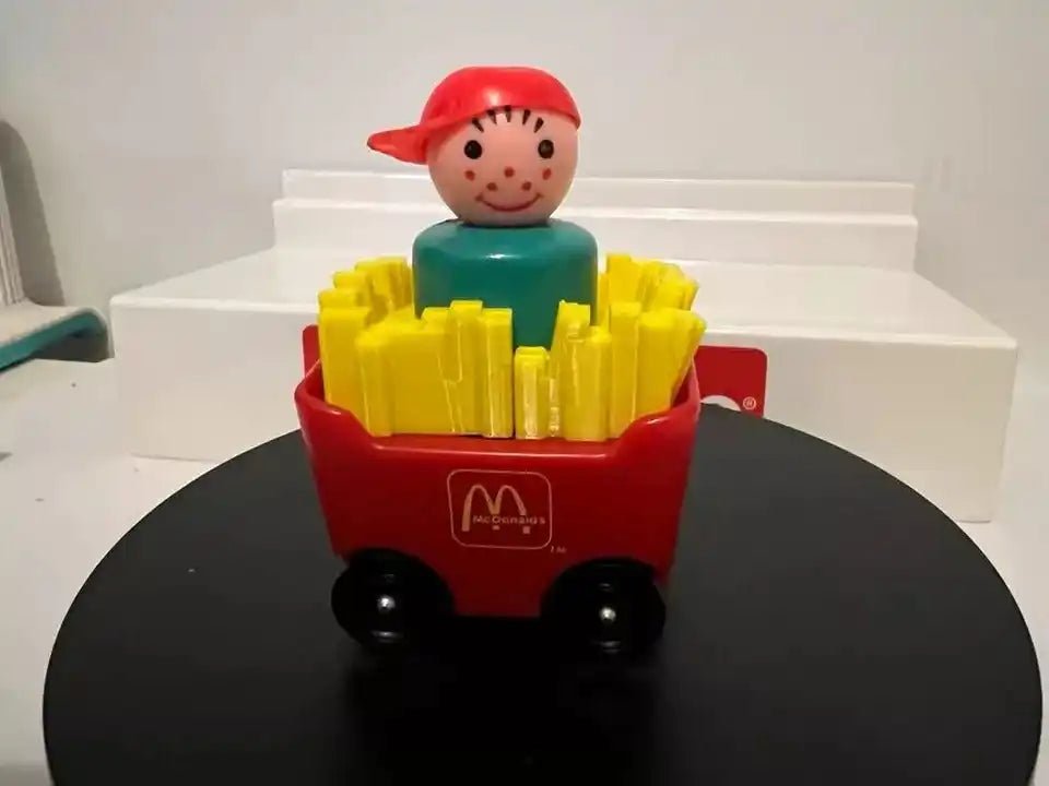 A custom 3D printed red McDonald's Little People Fry Car adapter with a figure and yellow fries, on a black and white surface.