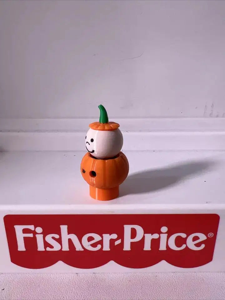 Orange pumpkin character figurine with white face and green stem cap