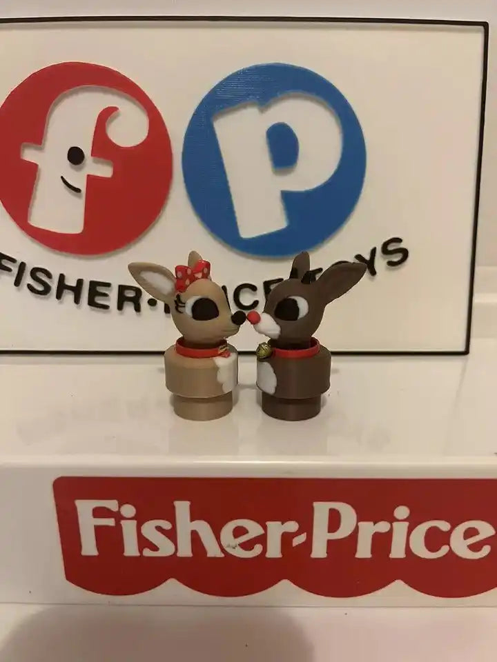 A custom 3D printed Clarice and Rudolph Little People style figures stand on a white surface in front of the Fisher-Price logo.