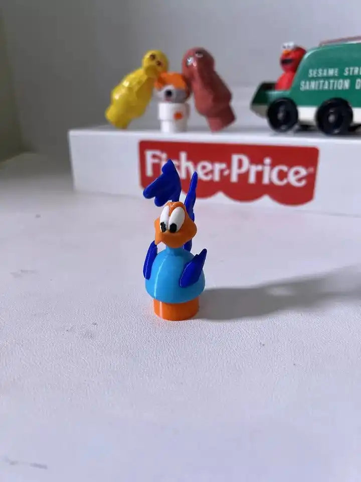 Blue Road Runner-style figurine with orange base and open-beak head, standing