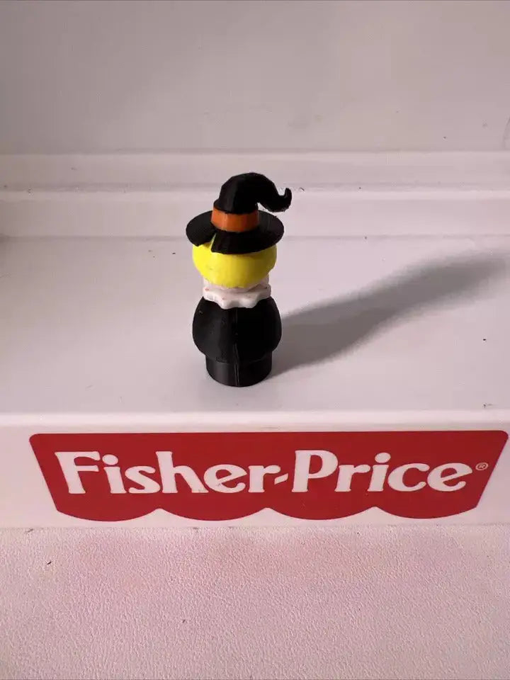 Halloween witch figurine with black hat and dress, white face, yellow collar detail.