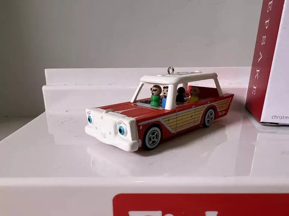 Red, yellow, and white station wagon ornament with two passenger figures inside